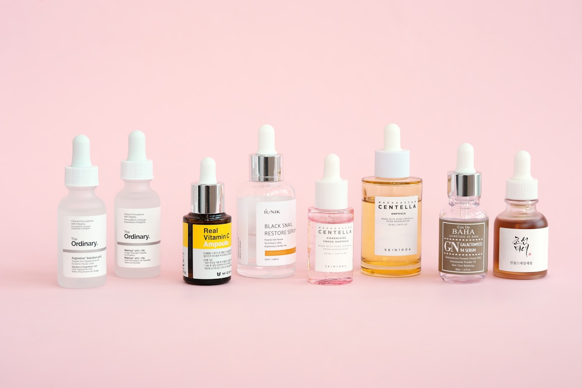 Routine skincare — bouteilles sur fond rose pastel
